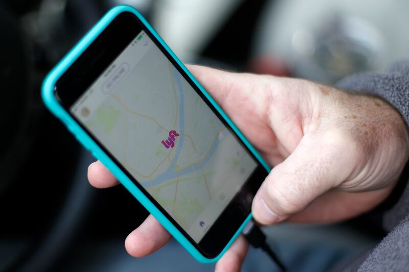 In this Jan. 31, 2018, photo, a Lyft driver opens the Lyft app on his phone while waiting for a fare in Pittsburgh. Downloading the Lyft app can get you discounts on rides for New Year's Eve.