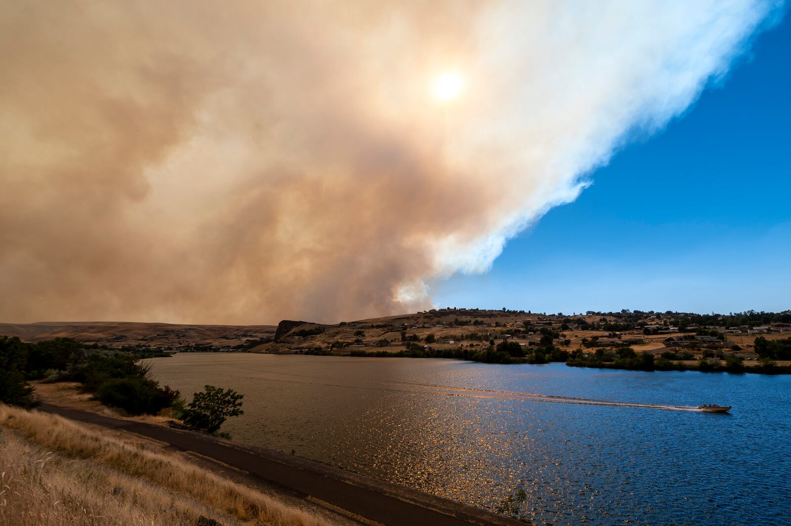A boat heads down the Snake River as smoke from a fire west of Clarkston, Wash., wafts eastward into Lewiston, Idaho.