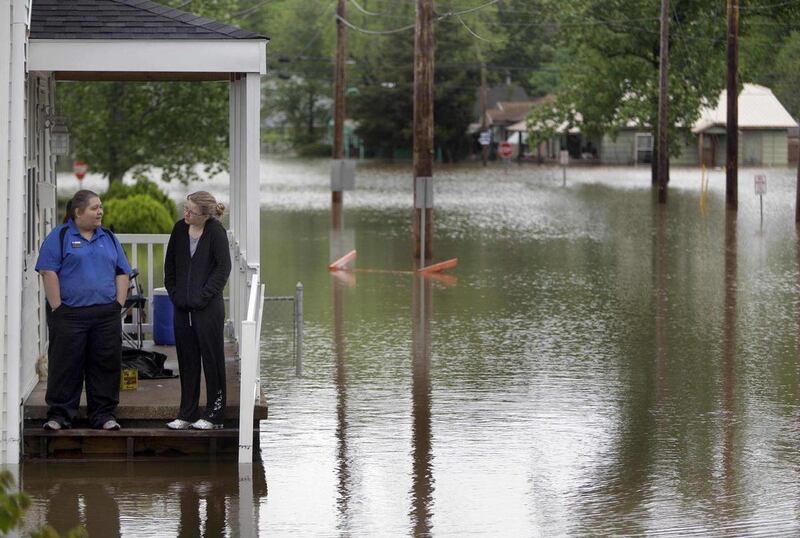 Kasey Medley, right, stands on the front porch of her flooded home with her friend Erica Cass Tuesday, April 26, 2011, in Poplar Bluff, Mo. Powerful storms that swept through the nation's midsection have pushed river levels to dangerous heights and are th