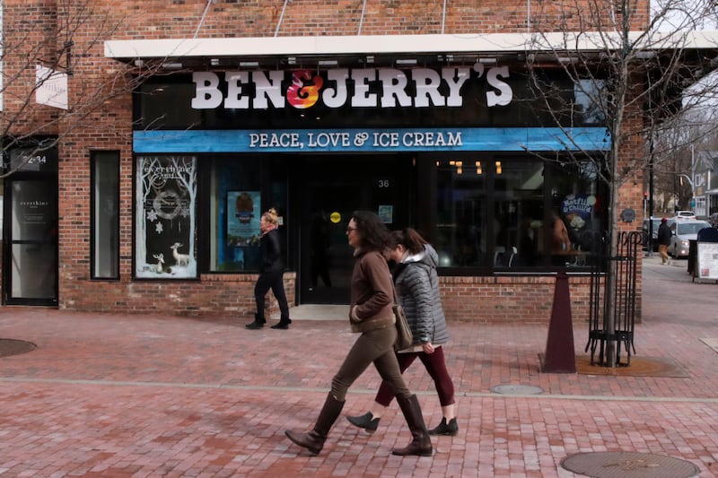Pedestrians walk on Church St., past the Ben & Jerry’s shop, in Burlington, Vt., Wednesday, March 11, 2020. (AP Photo/Charles Krupa)