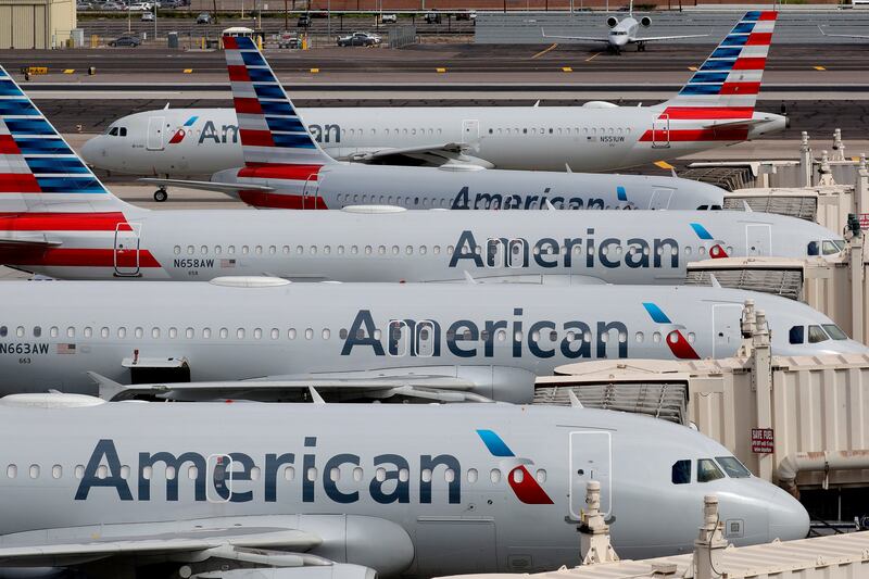 In this March 25, 2020, file photo, American Airlines jets sit idly at their gates as a jet arrives at Sky Harbor International Airport in Phoenix. American Airlines is telling 25,000 workers that they could lose their jobs in October because of the sharp drop in air travel during the virus pandemic.