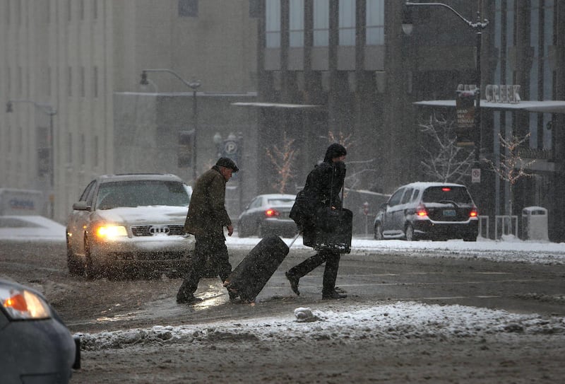 Pedestrians brave the icy and snowy streets in Salt Lake City on Thursday, Dec. 19, 2013.