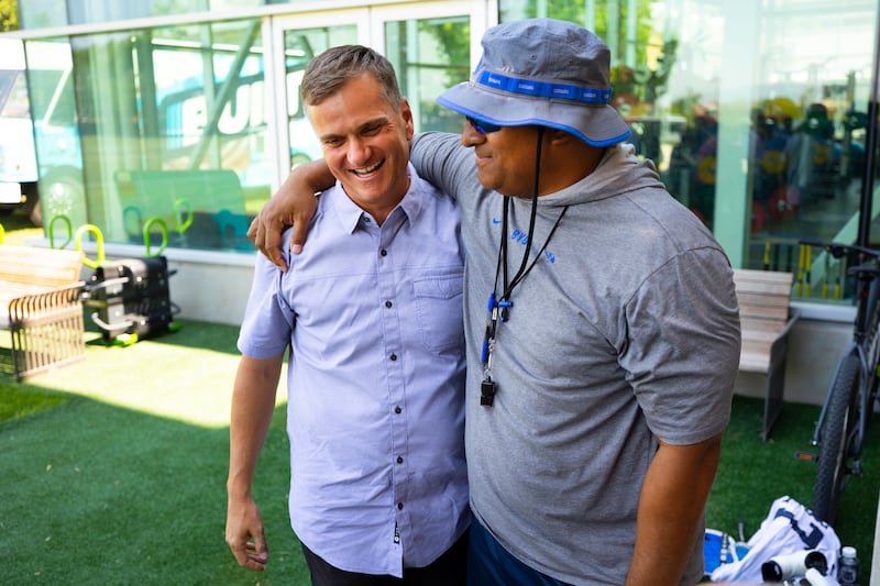 Nick Greer, co-founder of Built Brands, left, and BYU football coach Kalani Sitake greet each other during a press conference.