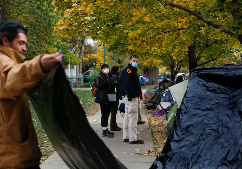 Salt Lake Police Detective Joseph Taylor and social worker Karen Montano watch as homeless people pack up their belongings in Taufer Park in Salt Lake City.
