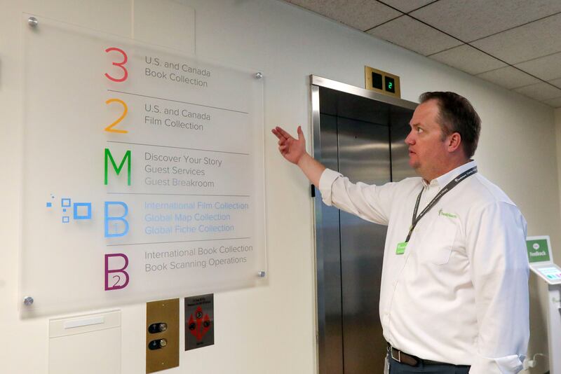 Lynn Turner shows the floor plan on a sign at the Family History Library.