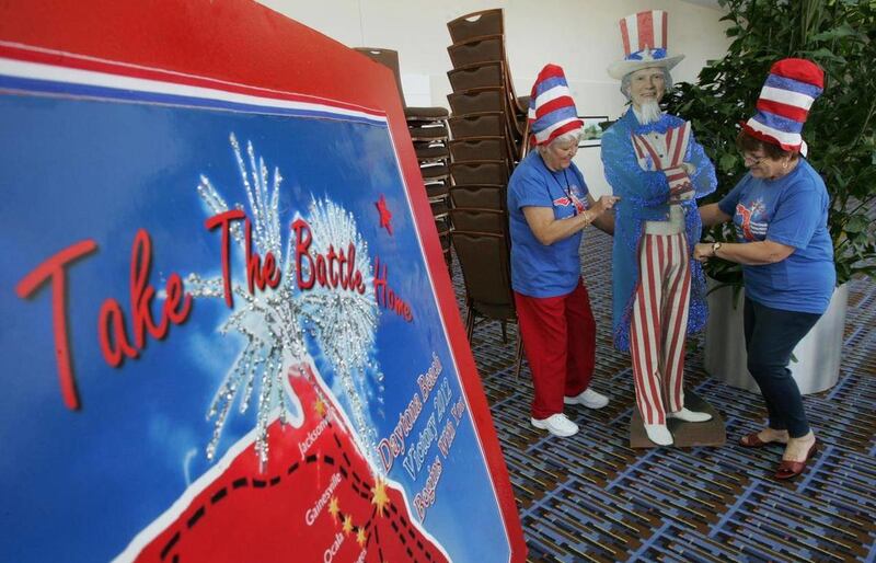 In this Thursday, Nov. 3, 2011 photo, Aileen Milton and Lynda DeHart slide a life-sized cutout of Uncle Sam in place while setting up for the Tea Party Convention in Daytona Beach, Fla., at the Ocean Center.