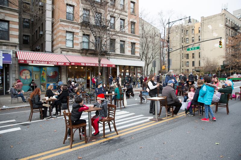 People eat at restaurant tables on a street block closed to vehicle traffic to allow social distancing and outdoor dining during the coronavirus pandemic in the borough of Manhattan in New York City on Sunday, December 13, 2020.