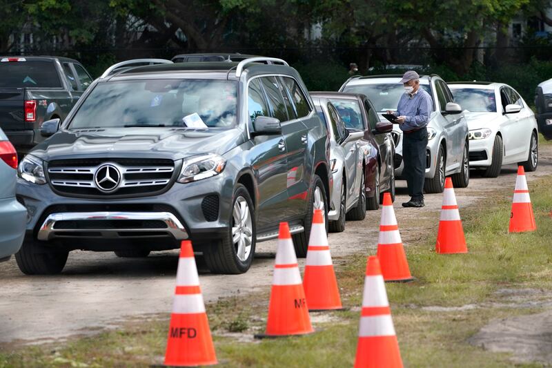 People in their vehicles are checked in at a drive-thru COVID-19 vaccination site at Marlins Park, Thursday, Jan. 21, 2021, in Miami.