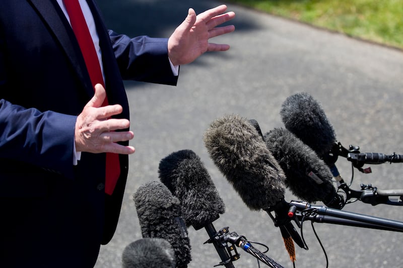 Microphones are extended as former President Donald Trump speaks with reporters on the South Lawn of the White House.
