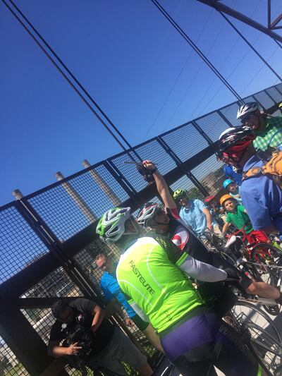 Davis County Commissioner Bret Millburn raises the "golden spoke" as riders from Ogden and Provo meet on the Jordan River Parkway bridge on Saturday, June 2, 2018. The ride commemorates the conjunction of a number of trails known as the Golden Spoke trail