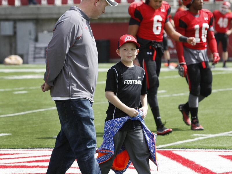 Young Max Brennan, who is fighting leukemia, walks off the field with his dad, Kyle Brennan, after helping call signals during a football scrimmage at Rice-Eccles Stadium Saturday, April 12, 2014, in Salt Lake City.