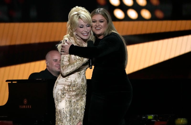 Dolly Parton and Kelly Clarkson hug on stage at the CMA awards.