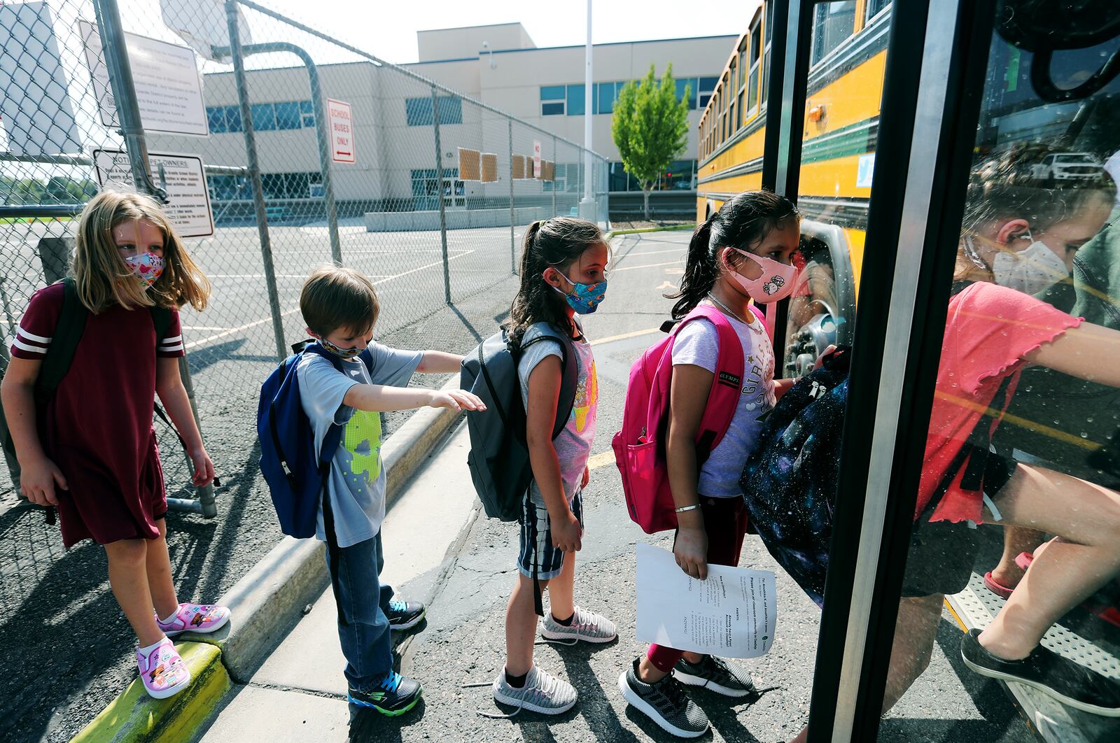 Students at Woodrow Wilson Elementary School in South Salt Lake wear masks as they get on a bus