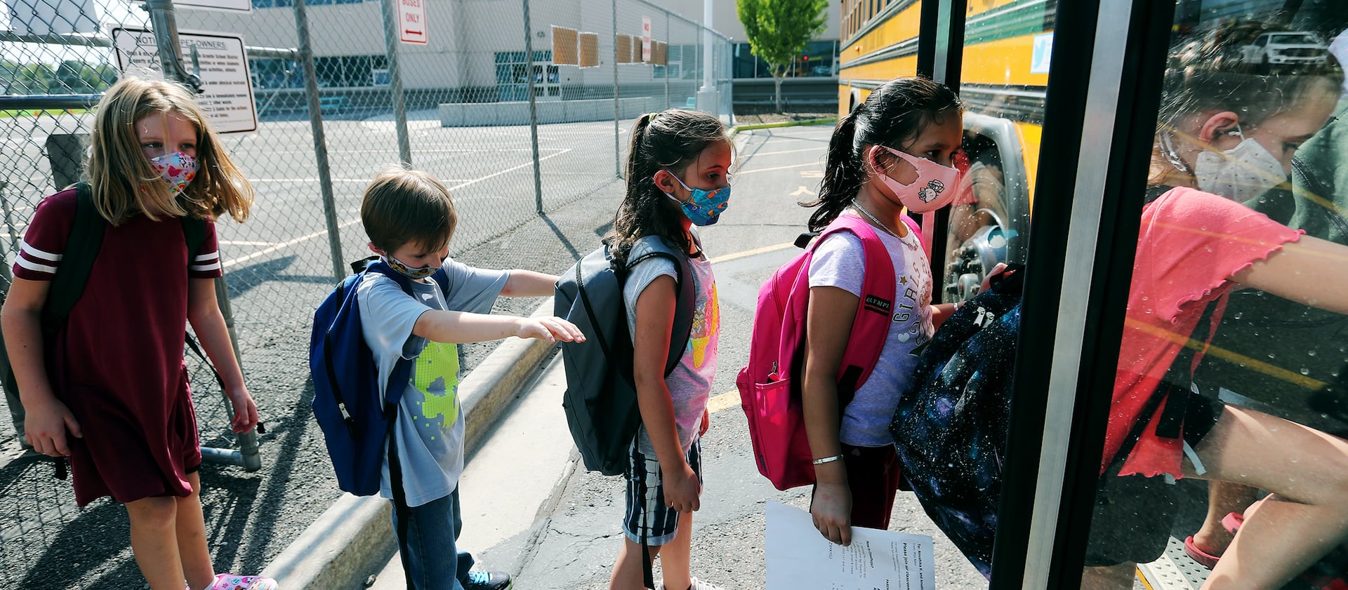 Students at Woodrow Wilson Elementary School in South Salt Lake wear masks as they get on a bus