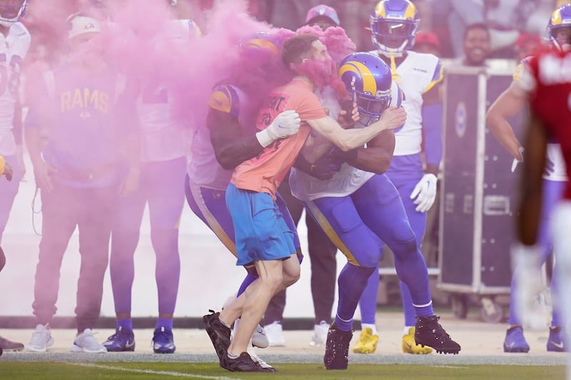 A protester is hit by Los Angeles Rams defensive end Takkarist McKinley, middle left, and linebacker Bobby Wagner during a game between the San Francisco 49ers and the Rams, Monday, Oct. 3, 2022.