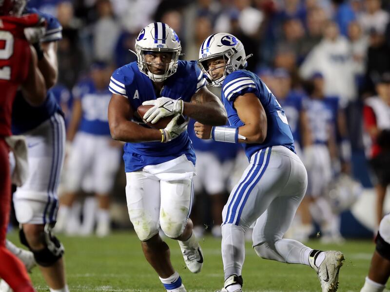 BYU running back Tyler Allgeier takes handoff from quarterback Jaren Hall as BYU and Utah play at LaVell Edwards Stadium.
