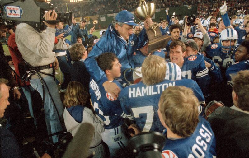 Brigham Young University football coach LaVell Edwards carries the trophy as he is carried off the field following BYU’s 24-17 victory over University of Michigan in the Holiday Bowl, Dec. 22, 1984 in San Diego.