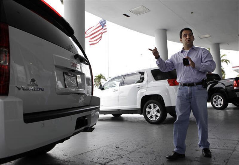 Fabricio Andrade looks at a GMC Yukon hybrid car at a dealership in Doral, Fla. Andrade wants to buy the Yukon and trade in his Lexus.