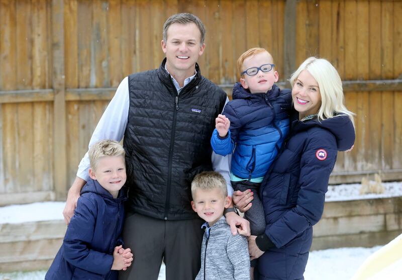 Blake Moore, his wife, and three of his sons stand in their yard on a snowy day.