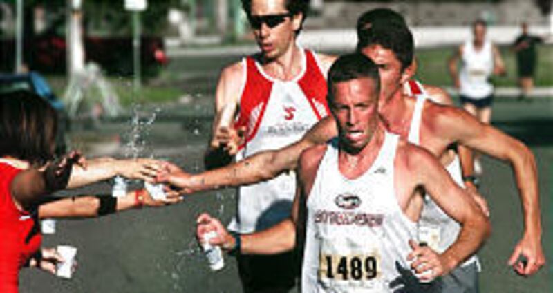 Joe Wilson, front, and other runners grab cups of water as they run in Saturday's Salt Lake Classic 10K.