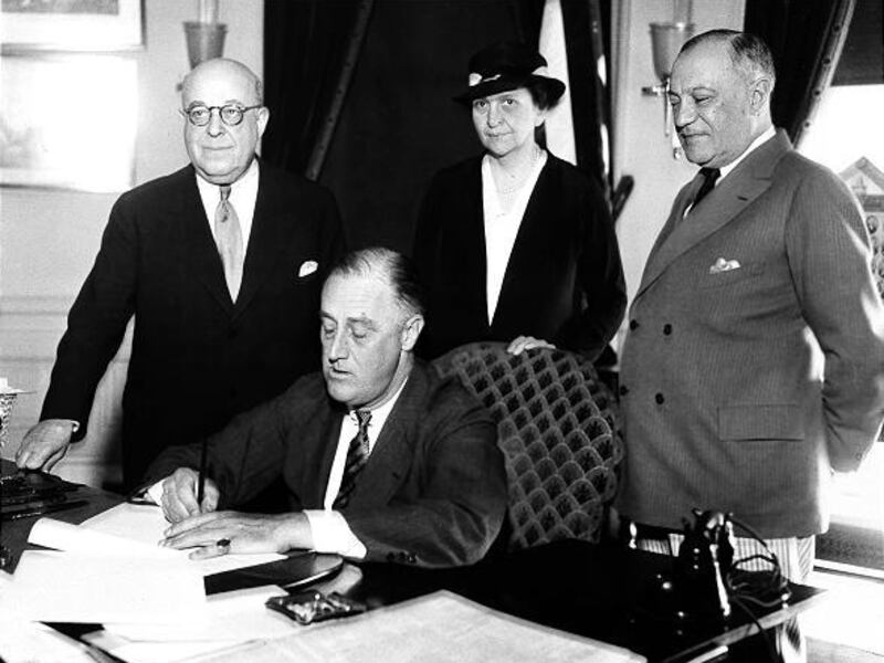 President Franklin D. Roosevelt signs the Wagner Unemployment Bill during the Great Depression with Rep. Theodore A. Peyser, D-N.Y.; Labor Secretary Frances Perkins and Sen. Robert Wagner, D-N.Y.