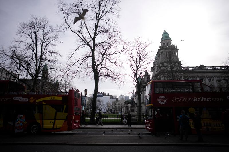 A seagull flies in between two tourist buses in Belfast city centre Northern Ireland.
