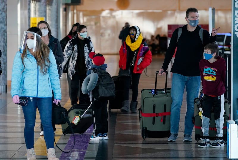 Travelers wear face masks while checking in at the ticket counter of Frontier Airlines in the main terminal of Denver International Airport late Thursday, Dec. 31, 2020, in Denver. Harvard University researchers said rapid testing at airports could reduce spread of COVID.