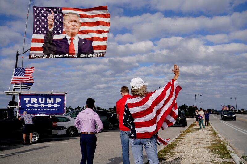 Evelyn Knapp, a supporter of former President Donald Trump, waves to passersby outside of Trump’s Mar-a-Lago estate.
