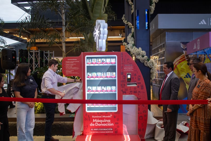 Representatives of the shopping center hosting the Giving Machines in San Salvador, El Salvador, unwrap the new machines on Nov. 13, 2025.