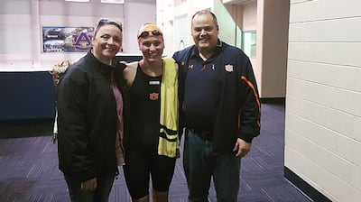 Zoe Thatcher, 22, poses with her Latter-day Saint Institute teacher, Mark Beesley, and his wife Carrie, at an Auburn University swim meet.