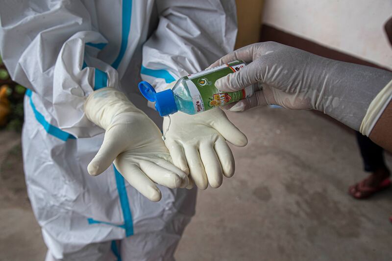 An Indian health worker wearing personnel protection equipment (PPE) kit sanitizes her hands as she takes nasal swab samples in Gauhati, India, Wednesday, July 8, 2020. India has overtaken Russia to become the third worst-affected nation by the coronavirus pandemic.