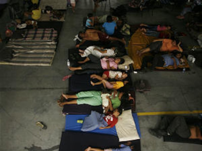 People rest on the floor of a warehouse in Nuevo Laredo, northeastern Mexico, after being evacuated from the nearby town of Ciudad Anahuac, Tuesday, July 6, 2010. About 18,000 people were evacuated Tuesday from Ciudad Anahuac where authorities opened a d