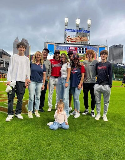 Daniel Schneemann poses with family members and friends on the Guardians field in Cleveland earlier this summer.
