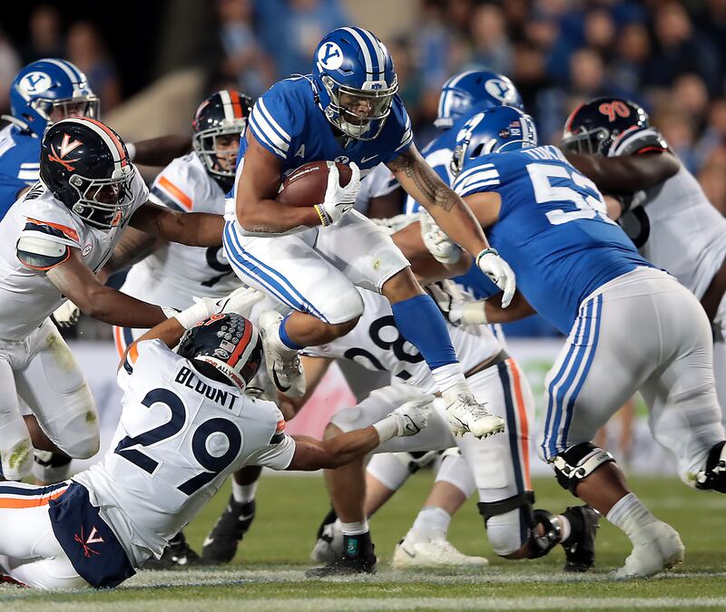 Brigham Young Cougars running back Tyler Allgeier (25) jumps over Virginia Cavaliers free safety Joey Blount (29).