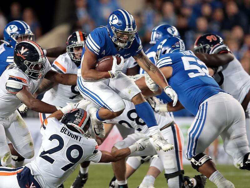 Brigham Young Cougars running back Tyler Allgeier (25) jumps over Virginia Cavaliers free safety Joey Blount (29).