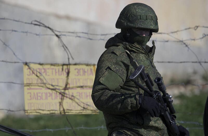 A Russian soldier guards a pier where two Ukrainian naval vessels are moored, in Sevastopol, Ukraine, on Wednesday, March 5, 2014. A Russian military truck broke down the gates of a Ukrainian base in the Crimean port city of Sevastopol and the installatio
