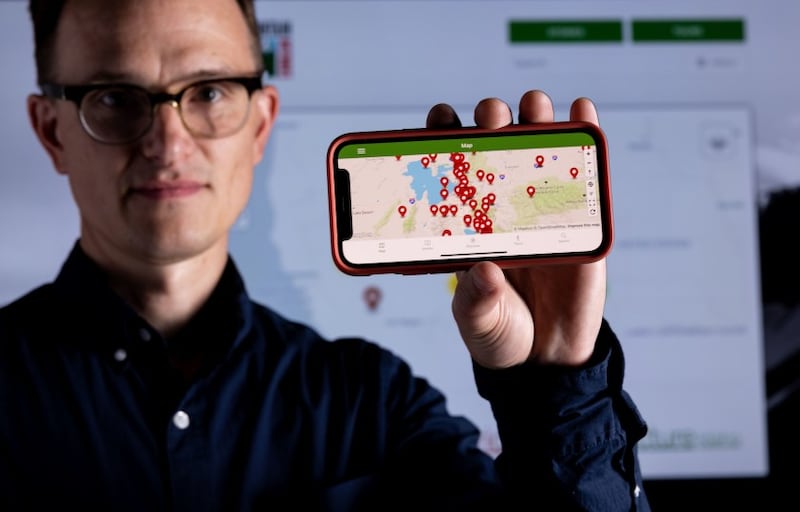 BYU history professor Brenden Rensink holds up his phone displaying a new app called “Intermountain Histories.”