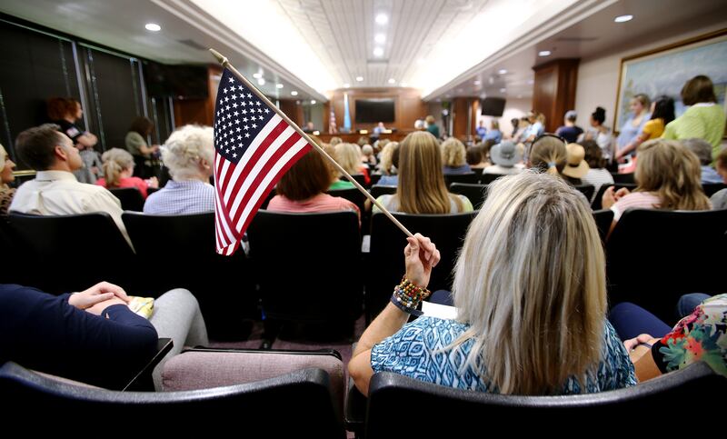 A woman holds an American flag during a Utah County Commission meeting.