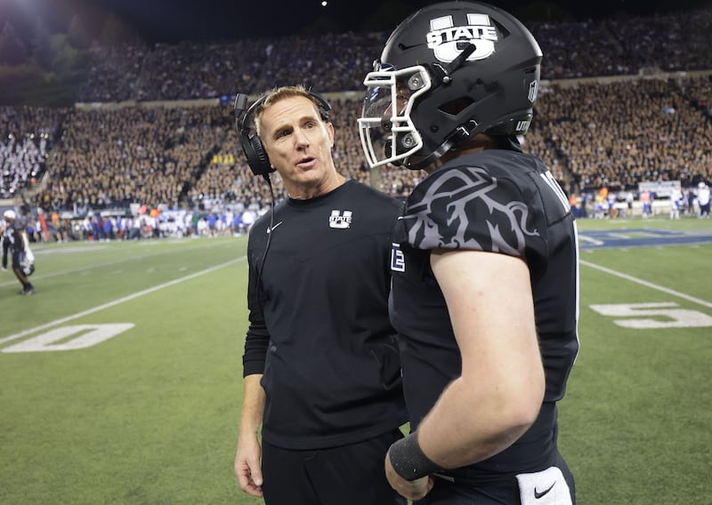 Utah State Aggies head coach Blake Anderson talks with Aggies quarterback Logan Bonner.
