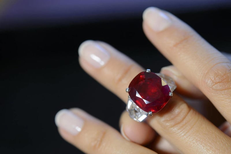 FILE - This May 6, 2015 file photo shows a Sotheby's employee wearing a ruby and diamond ring by Cartier, with a Burmese ruby weighing 25.59 carats, during a preview at the Sotheby's auction house in Geneva, Switzerland. The ring sold for $30.3 million at