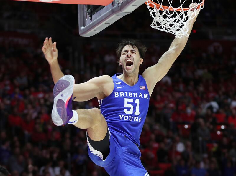 BYU forward Gavin Baxter hangs on the rim after dunking during game against the Utes in Salt Lake City on Nov. 27, 2021.