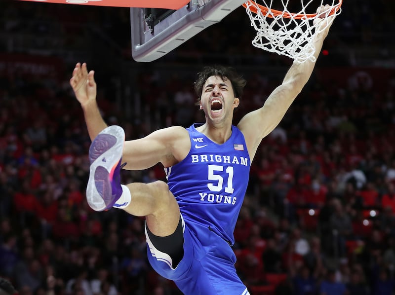 BYU forward Gavin Baxter hangs on the rim after dunking during game against the Utes in Salt Lake City on Nov. 27, 2021.