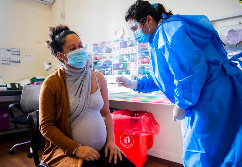 A nurse gives a shot of the Pfizer vaccine for COVID-19 to a pregnant woman.
