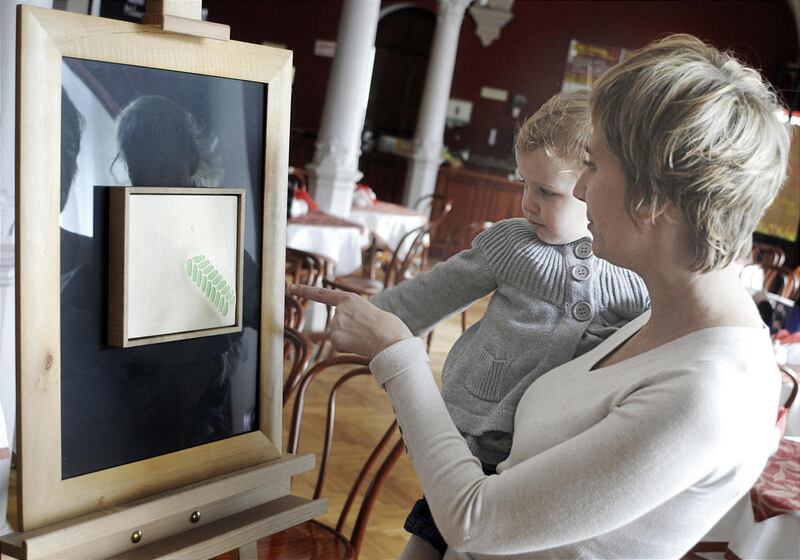 A mother and child point a small painting by art student Andrzej Sobiepan at the caf?of the National Museum in Wroclaw, Poland on Wednesday, Jan. 4, 2012. Art student Andrzej Sobiepan didn't want to wait decades for his work to appear in museums. So he