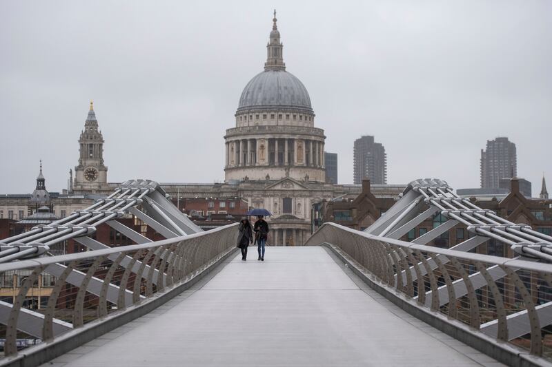 People walk across the Millennium Bridge in London, Monday Dec. 21, 2020. Millions of people in England have learned they must cancel their Christmas get-togethers and holiday shopping trips.