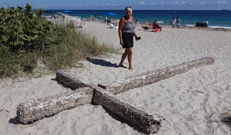 Aglair Rigos checks out a cross on the Galt Ocean Mile behind the Ocean Manor Beach Resort, in Fort Lauderdale, Florida, on Tuesday, Feb. 5, 2019. The large, barnacle-covered wooden cross washed ashore along the South Florida beach, captivating tourists,