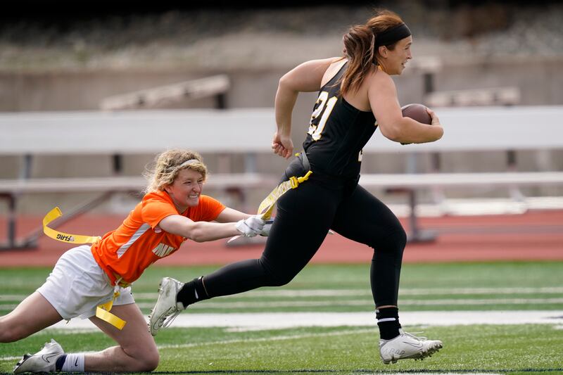 Ottawa quarterback Madysen Carrera (21) is tackled by Midland defender Casey Thompson during an NAIA flag football game in Ottawa, Kan.