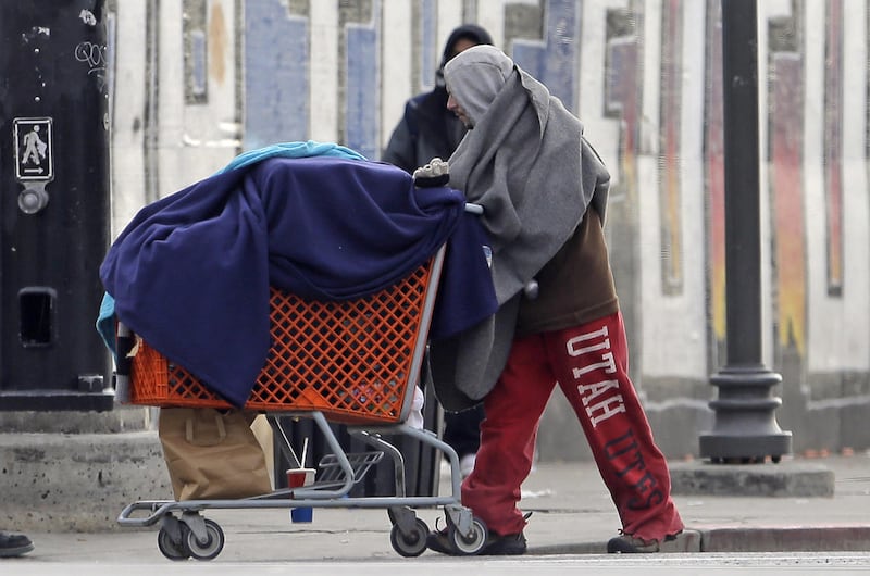 A person pushes a cart downtown Tuesday, Dec. 13, 2016, in Salt Lake City. Salt Lake City is preparing to close an overflowing downtown homeless shelter that's been the scene of violence like a police shooting that critically injured a teenage refugee, bu