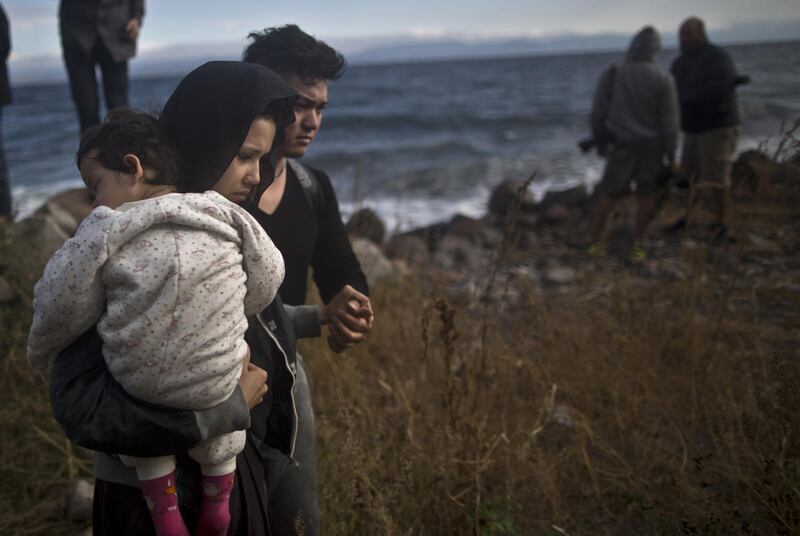 An Afghan refugee family walks toward the main road after arriving on a dinghy from the Turkish coast to the northeastern Greek island of Lesbos, Friday, Oct. 2 , 2015. The International Organization for Migration says a record number of people have cross