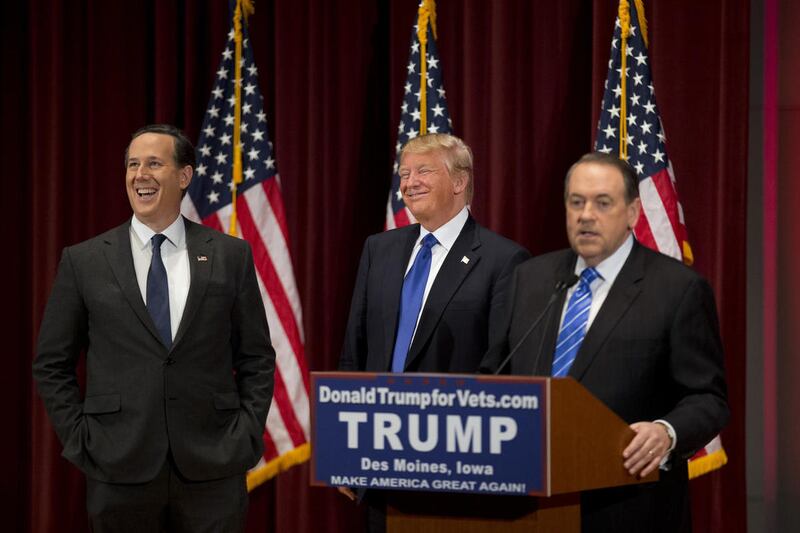 Republican presidential candidates Rick Santorum, left, and Donald Trump, center, laugh as they listen to Mike Huckabee during a campaign event on the campus of Drake University Thursday, Jan. 28, 2016, in Des Moines, Iowa.
